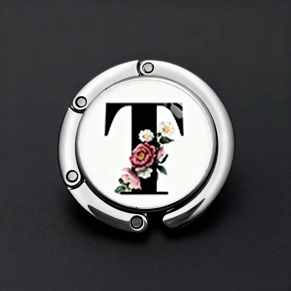 Silver foldable letter hanger hook with a floral design on a black background
