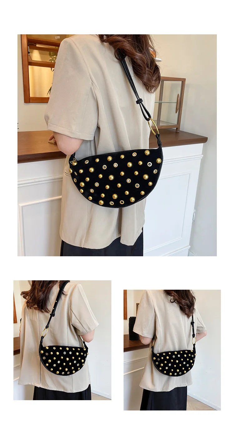 A woman models a black faux suede hobo crossbody bag with gold rivet accents against a light background.