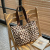 A brown and beige striped corduroy tote bag is displayed on a wooden chair against a slatted window background.