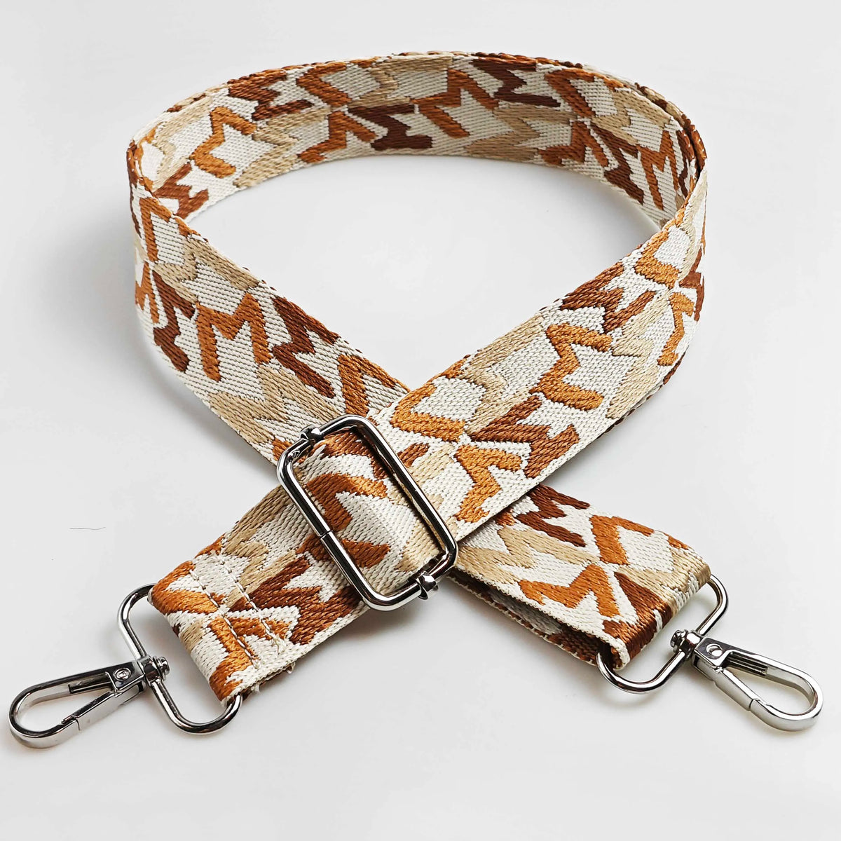 A beige and brown jacquard patterned strap for an adjustable wide crossbody bag.