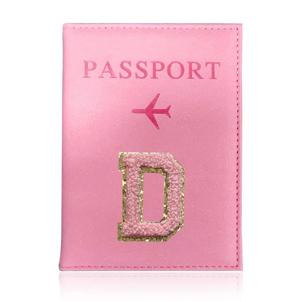 A pink leather passport holder with a gold embossed letter D and a pink airplane symbol.