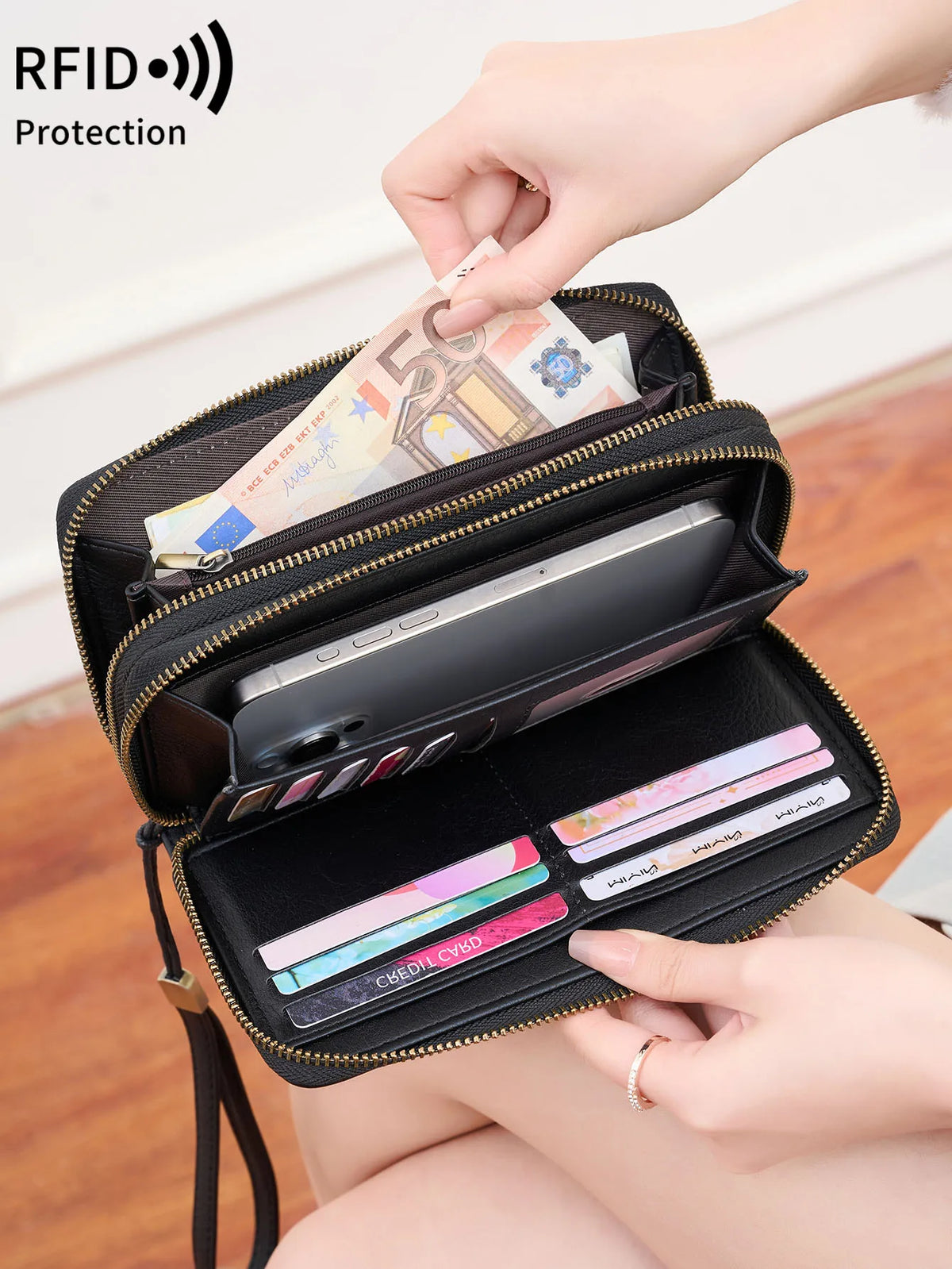 A hand is opening a black double-zipper wallet to show protection against RFID scanning.