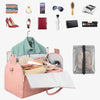 A collection of various accessories and a pink foldable garment duffle bag for travel.