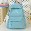 A light blue nylon backpack with a white bow and decorative lace trim is shown against a white background.