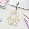 A clear acrylic photocard holder featuring a heart design and angel wings, suspended by a silver charm.