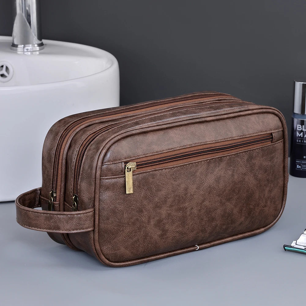 A brown premium PU leather toiletry bag with a gold zipper is shown next to a white ceramic sink.