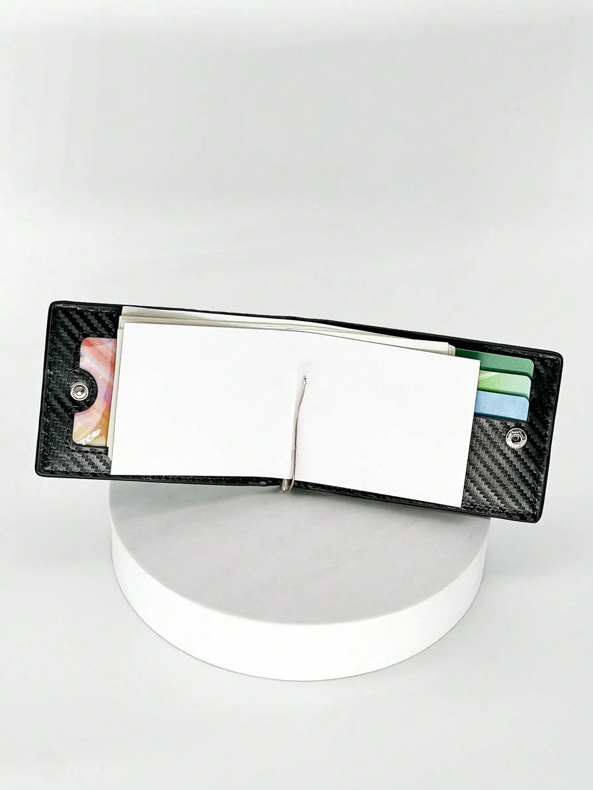 Estuche para tarjeta de fibra de carbono negra con tarjeta blanca y tarjetas de plástico de colores dentro.