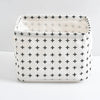 A white storage basket with a grid pattern of black crosses and handles.