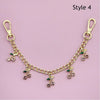 Gold decorative chain necklace with small green and pink floral pendants and a lobster clasp.
