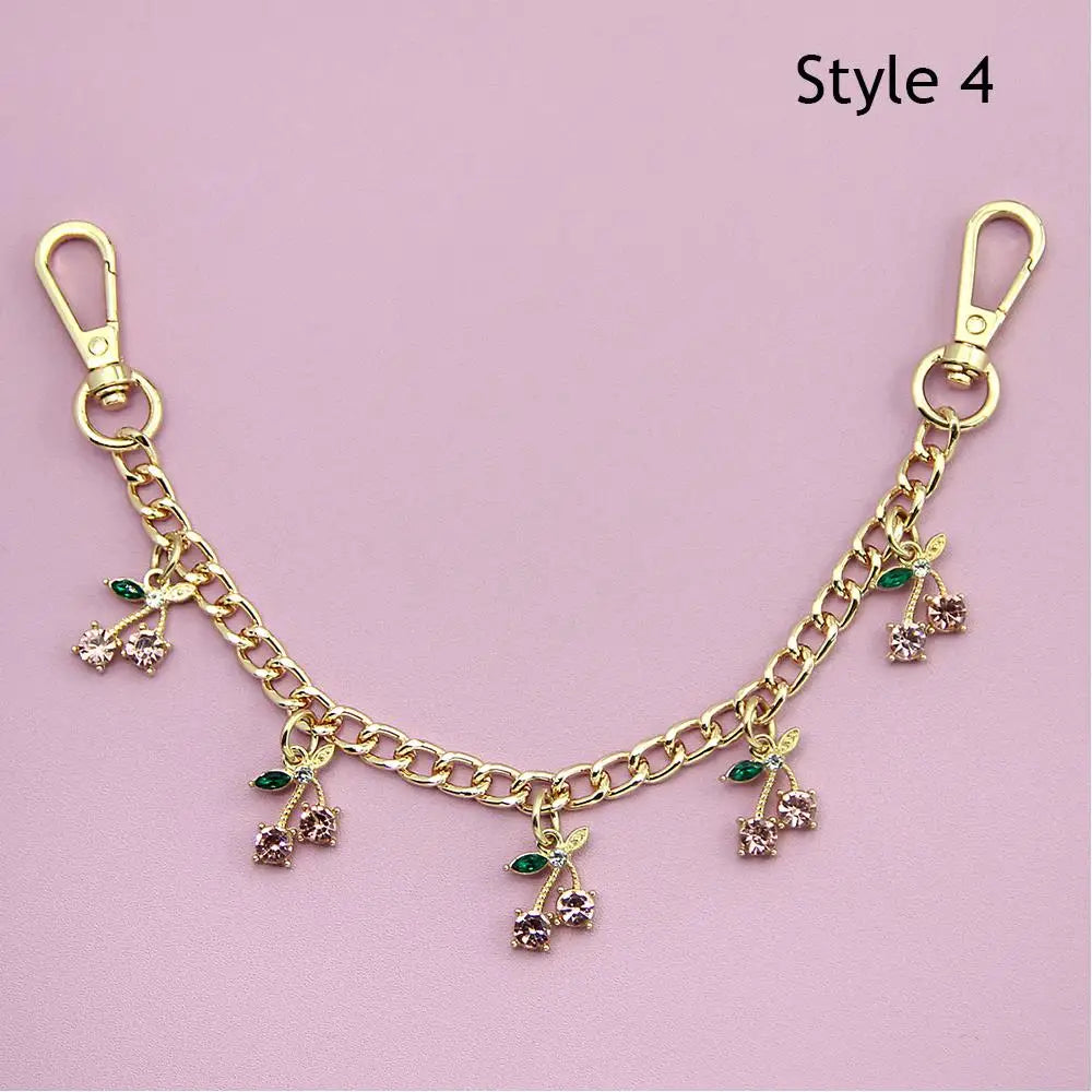 Gold decorative chain necklace with small green and pink floral pendants and a lobster clasp.