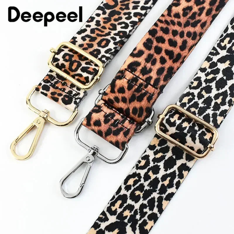 A close-up of a leopard print adjustable strap for bags featuring gold-toned buckles.