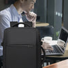 A dark gray men's business travel backpack resting on a wooden table next to a laptop.