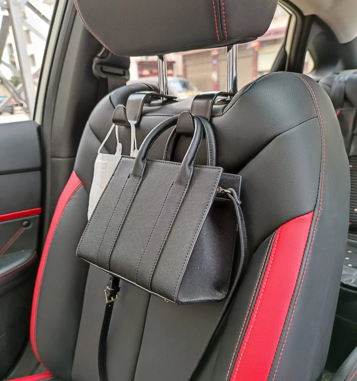 Black car seat back hooks with a red accent strap are visible inside a vehicle.