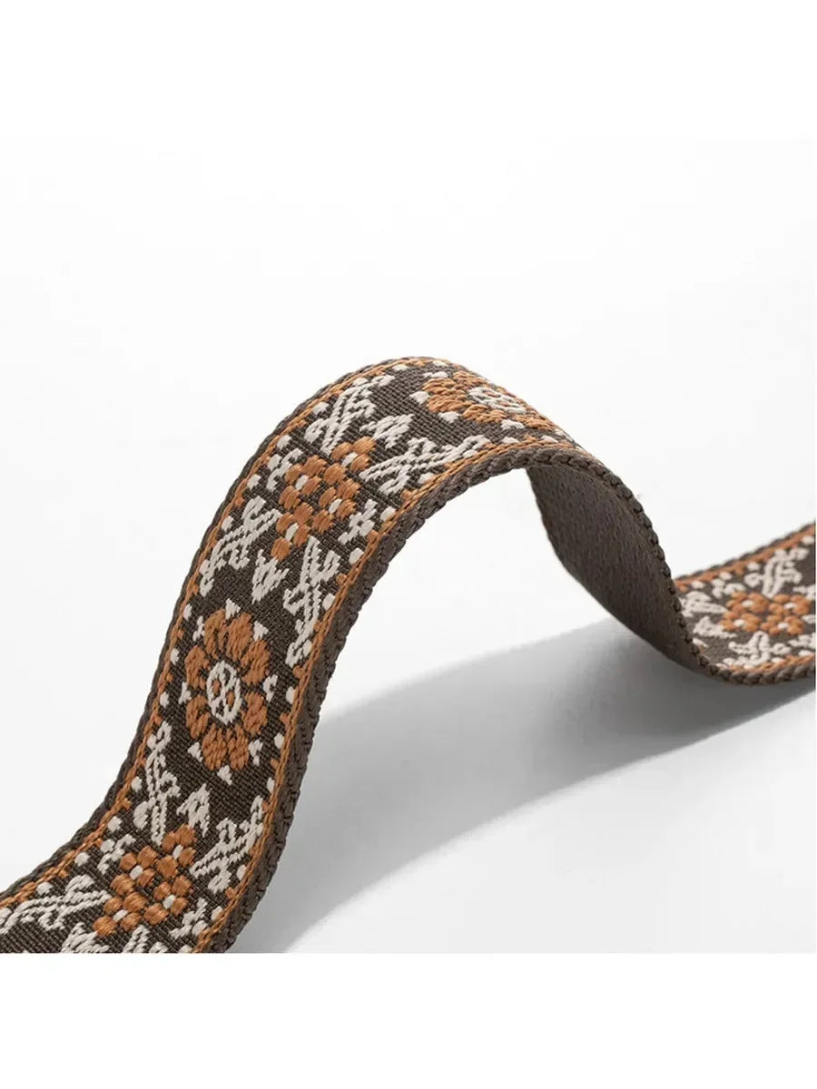 A close-up of a brown and beige patterned textile replacement bag strap.