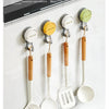 A set of silicone and wood traceless suction cup hooks for kitchen use mounted on a white cabinet door.