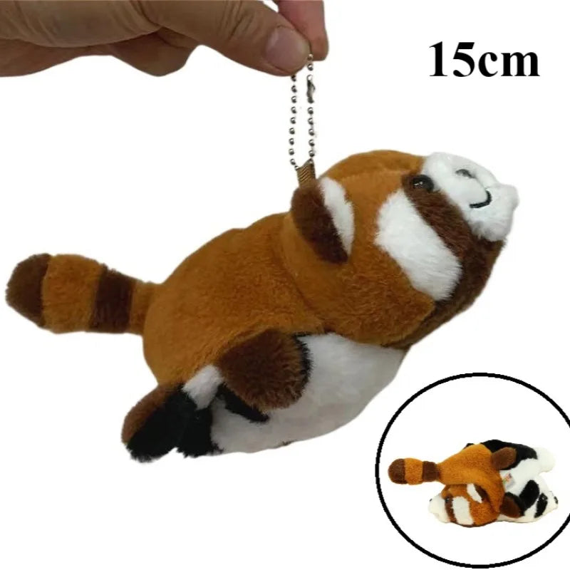 A brown and white red panda plush toy with a hanging charm, shown next to a hand for scale.