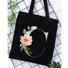 Black canvas tote bag featuring an alphabet floral print with a rose design.