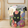 A purple storage basket filled with folded gray and cream textiles featuring a floral pattern with a black cat face.