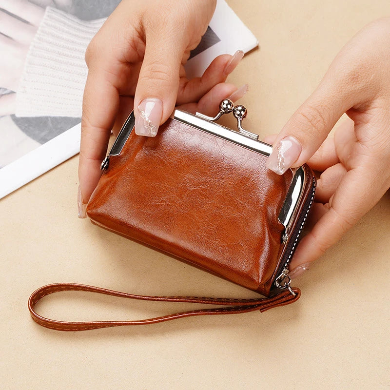 A hand holds a brown vintage PU leather compact wallet with a coin pocket and leather strap.