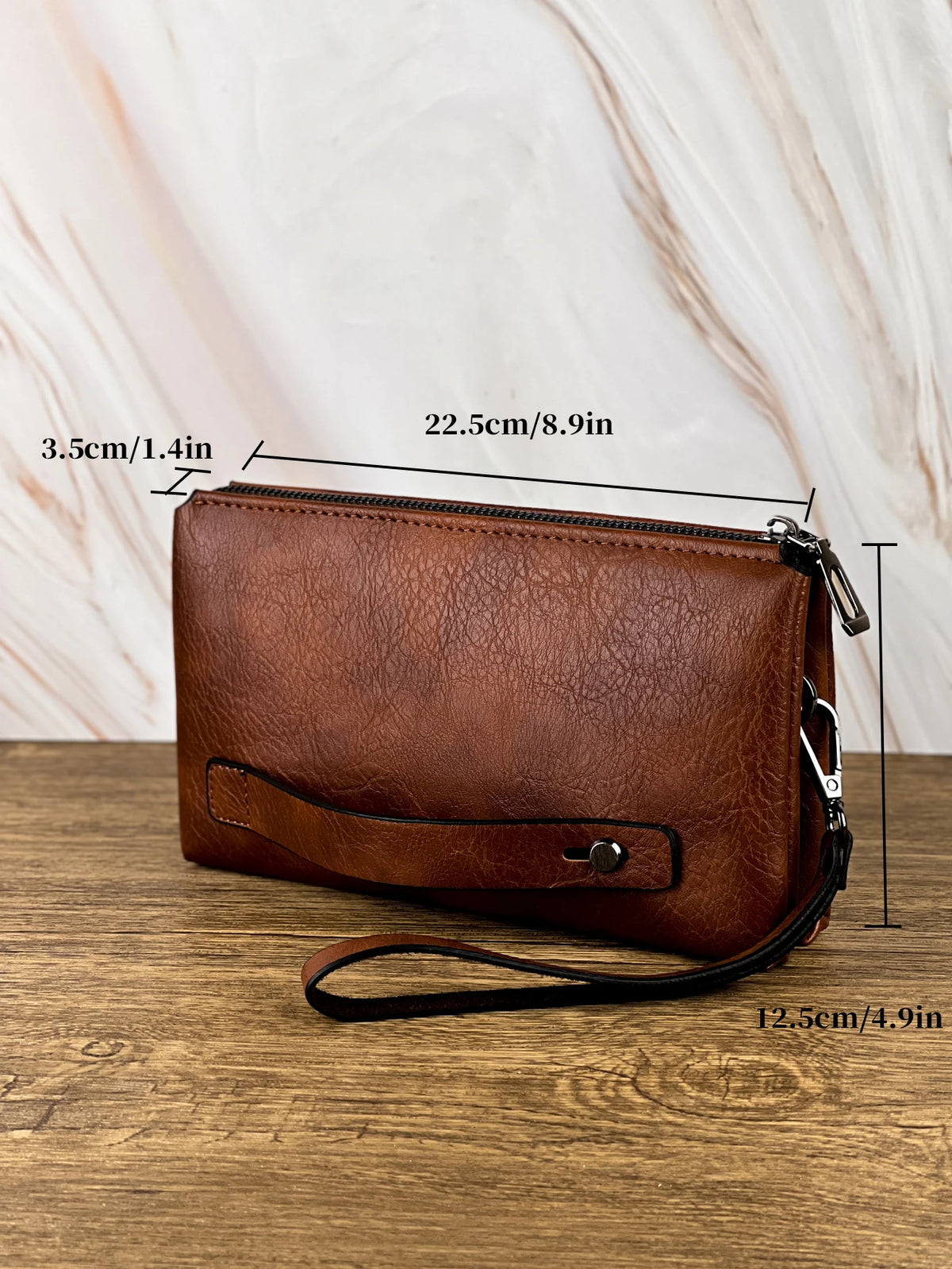 Portefeuille pochette en cuir marron posé sur une surface en bois avec des lignes de mesure.
