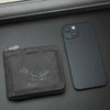 Cartera de tarjetas vintage negra con relieve para hombre junto a un smartphone oscuro.