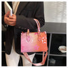 A pink and orange ladies shoulder tote bag is held by a person wearing a black blazer.