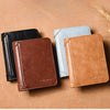 Three luxury PU leather men's wallets in black, light blue, and tan resting on a brown surface.