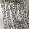 A close-up of clear, faceted crystal glass beads in a wheel shape strung together for jewelry making.