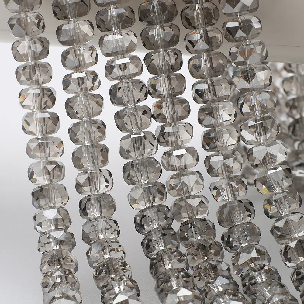 A close-up of clear, faceted crystal glass beads in a wheel shape strung together for jewelry making.