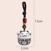 A silver lucky cat charm keychain with a dark brown beaded string and measuring lines.