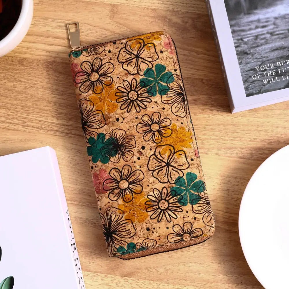 A close-up of a bohemian wood-grain leather wallet featuring floral patterns in orange, green, and brown tones on a wooden su