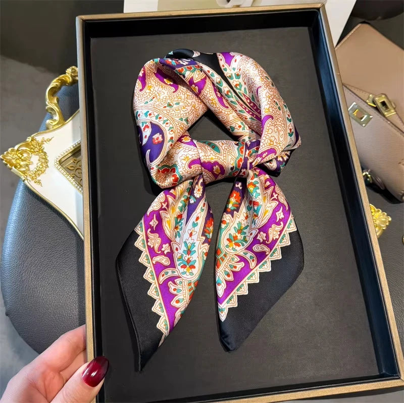An elegant paisley silk hair scarf and headband tied in a bow, displayed in a black frame.