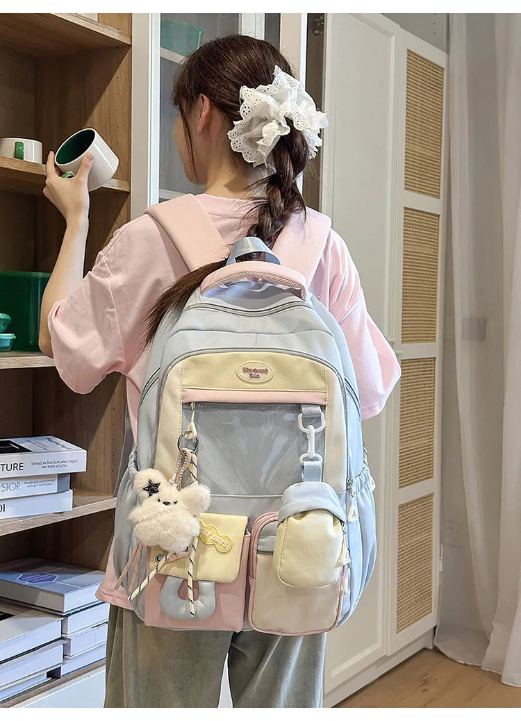 A young woman is wearing a light pink shirt and carrying a light blue backpack with yellow accents in a closet setting.