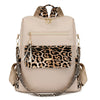 A beige fashion backpack featuring a leopard print flap and gold hardware.