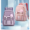 A pink canvas backpack with a plaid pattern and pink accents is displayed on a light blue stand.