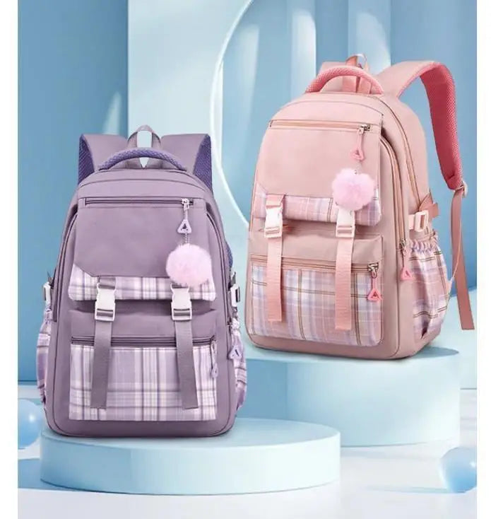 A pink canvas backpack with a plaid pattern and pink accents is displayed on a light blue stand.