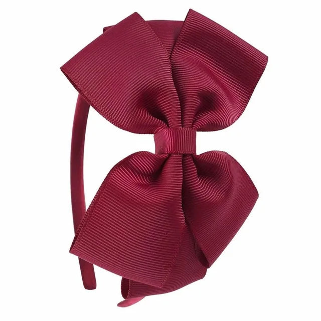 A close-up view of a deep magenta satin bow headband.