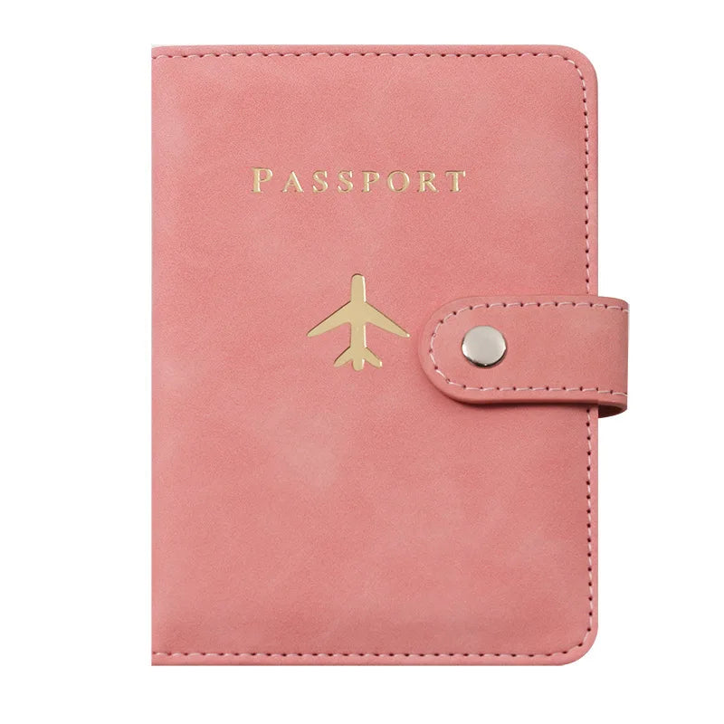 Porte-passeport en cuir rose avec texte gravé or et emblème d'avion doré.