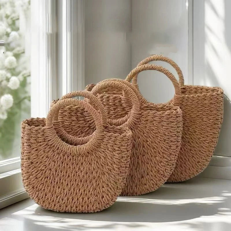 Three handwoven rattan beach bags in a natural tan color resting on a windowsill.