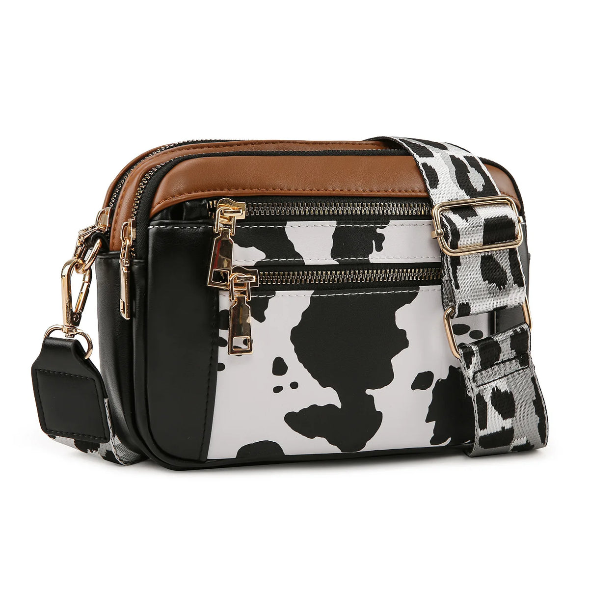 A black and white cow print PU leather crossbody bag with brown trim and gold hardware.