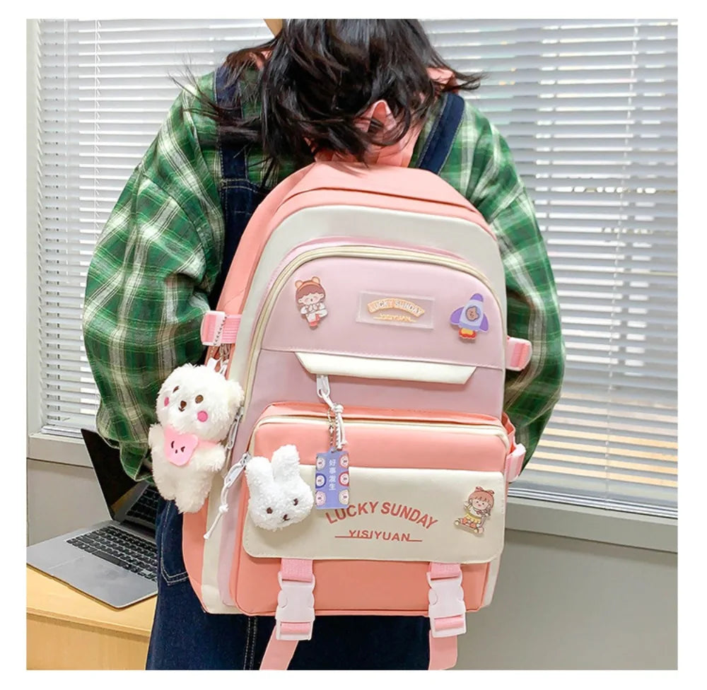 A person is wearing a pink nylon backpack set with cartoon designs in front of a window.