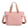 A light pink durable nylon tote bag with tan straps and a secure zipper closure.