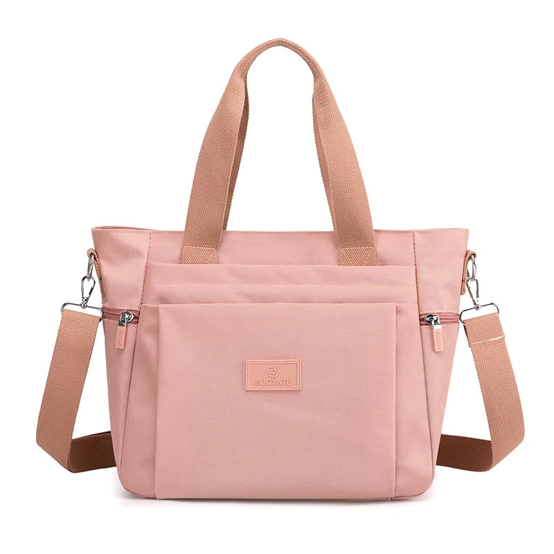 A light pink durable nylon tote bag with tan straps and a secure zipper closure.
