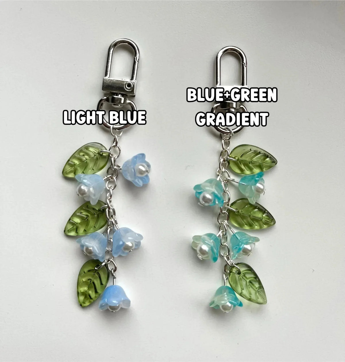 Pair of silver-hooked keychains featuring a blue to green gradient design with lily of the valley flowers.