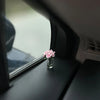 Eine kleine Glasvase mit rosa Rosen auf einer Auto-Innenausstattung.