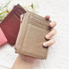 A hand holds a tan genuine leather zipper card holder and coin purse next to a pink one on a white textured surface.