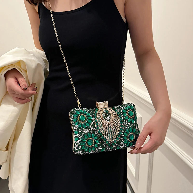 A woman holds a green rhinestone evening clutch bag against a black dress.