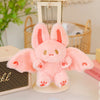 A pink bat bunny plush toy with large ears and soft wings is displayed on a light-colored stand.
