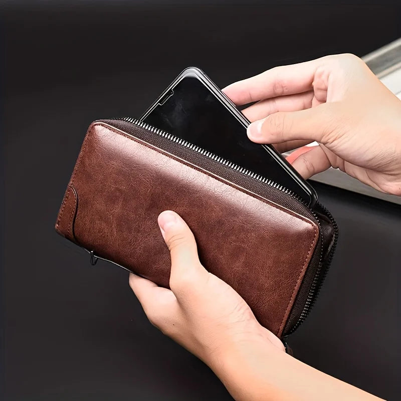 A hand is holding a brown PU leather zipper wallet for business.