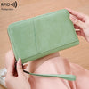 A light green leather RFID blocking travel wallet is shown being held by a person.